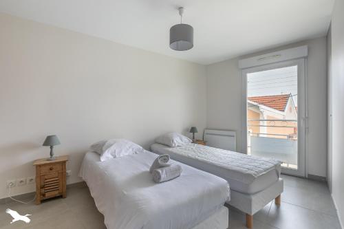 deux lits dans une chambre blanche avec une fenêtre dans l'établissement Villa Rose des sables, à Arcachon