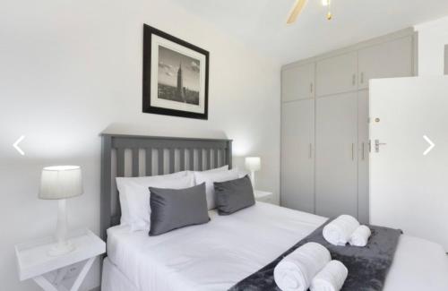 a bedroom with a bed with white sheets and pillows at Beautiful Beachfront apartment in Cape Town