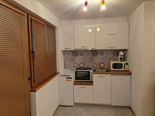 eine Küche mit weißen Schränken und einer Mikrowelle in der Unterkunft Victory in Stara Sagora
