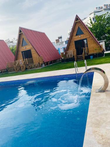 a pool with two cottages in the background at NOEL BUNGALOV & CAFE in Demre