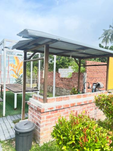 a patio with a black umbrella on a brick wall at Chantara Cottage in Kampung Mawar