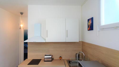 a kitchen with white cabinets and a sink at Appartement La Rotonde in Montluçon