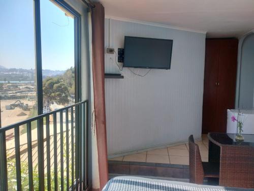 Pokój z balkonem z dużym oknem i telewizorem w obiekcie Pingüino en la roca - Concón w mieście Concón