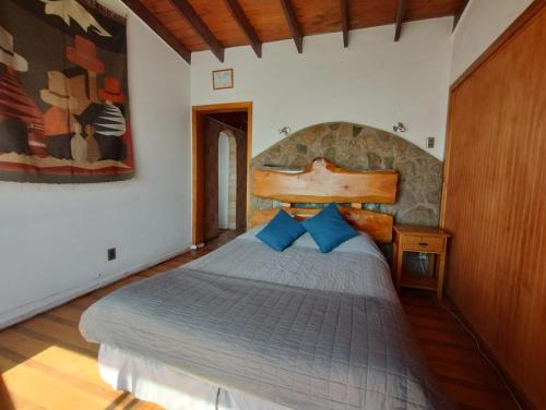a bedroom with a large bed with blue pillows at Pingüino en la roca - Concón in Concón