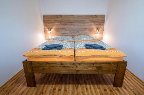a wooden bed with blue pillows in a bedroom at Penzion a vinařství Vyskočil Strachotín in Strachotín