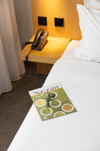 a book on a bed with a phone on a table at Evora Olive Hotel in Évora