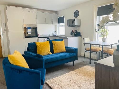 a living room with a blue couch and yellow pillows at The Seacroft in Southport