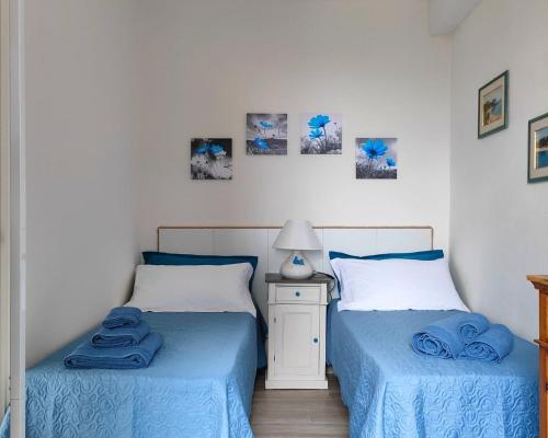 two beds in a bedroom with blue sheets at Dommu de Anna Murru in Baunei