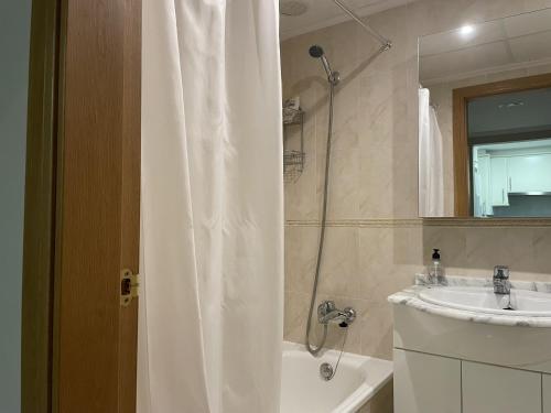 a bathroom with a shower curtain and a sink at Residencial Mar de Denia 2 in Denia