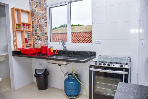 uma cozinha com um lavatório, um fogão e uma janela em Casa com Wi-Fi a 400 metros da Praia Maracanã-SP em Solemar