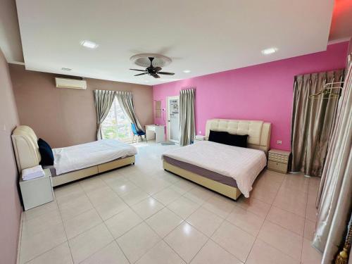 a bedroom with two beds and a pink wall at Paddy Village Multi Homestay in Sekinchan