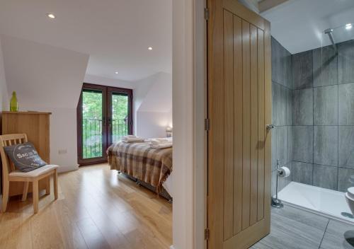a bedroom with a bed and a bathroom with a shower at Tai Marian Group Cottages in Llangadwaladr
