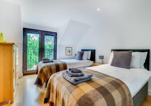 a bedroom with two beds and a window at Tai Marian Group Cottages in Llangadwaladr