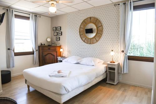 ein Schlafzimmer mit einem großen weißen Bett und einem Spiegel in der Unterkunft Le Cabanon - Maison 2 ch avec jardin et parking in Marseille