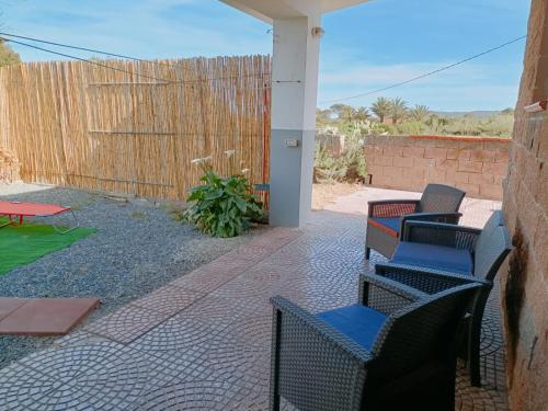 a patio with chairs and a table and a fence at Casa vacanza Ligustro appartamento il toro in SantʼAntìoco