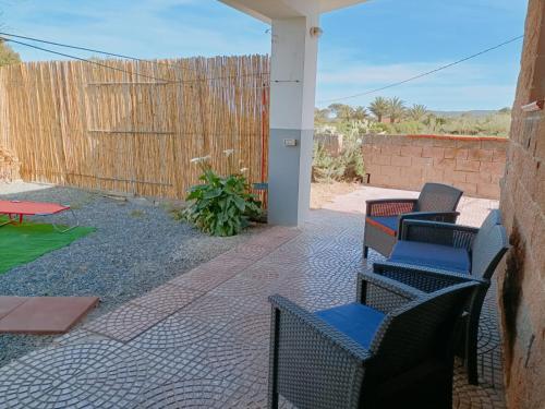 patio z krzesłami, stołem i ogrodzeniem w obiekcie Casa vacanza Ligustro appartamento il toro w mieście SantʼAntìoco