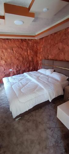 duże białe łóżko w pokoju z ceglaną ścianą w obiekcie Asem Studio apartment w mieście Wadi Musa
