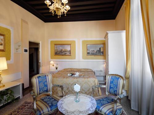 a bedroom with a bed and two chairs and a table at Hotel Corte dei Greci in Venice
