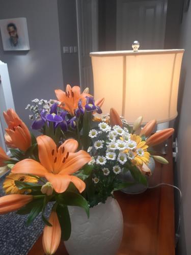 a vase of flowers on a table next to a lamp at Killossy Lodge in Naas