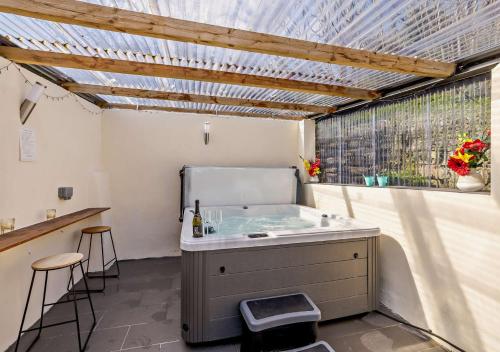 een badkamer met een bad, een raam en een wastafel bij Ysgubor y Graig in Halkyn