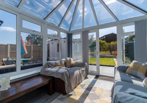 a conservatory with a glass roof with a couch at Valley Rise By My Getaways Free Parking in Portslade
