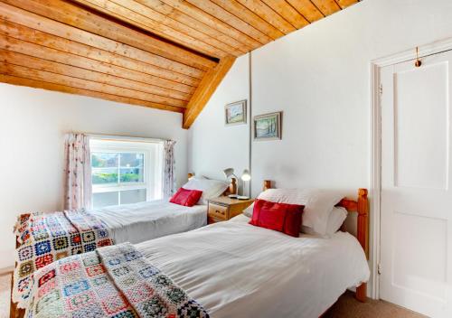 a bedroom with two beds and a window at West End Cottage in Llangennith