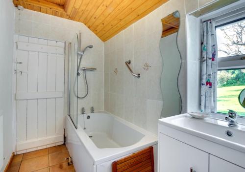 a bathroom with a tub and a shower and a sink at West End Cottage in Llangennith