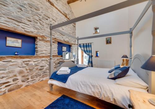 a bedroom with a bed and a stone wall at Ysgubor y Berwyn in Llanarmon Dyffryn-Ceiriog