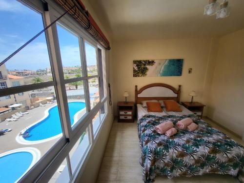 a bedroom with a bed and a view of a pool at Apartment next to Ajabo Beach Pool & Ocean view in Callao Salvaje