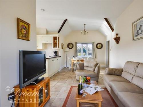 a living room with a couch and a tv and a kitchen at Frome Lodge House in Dorchester