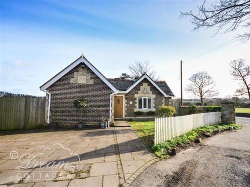 a brick house with a fence in front of it at Frome Lodge House in Dorchester