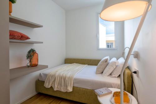 a bedroom with a bed with a lamp and a window at The Fetch - Residenze Esclusive sull'Acqua in Alghero