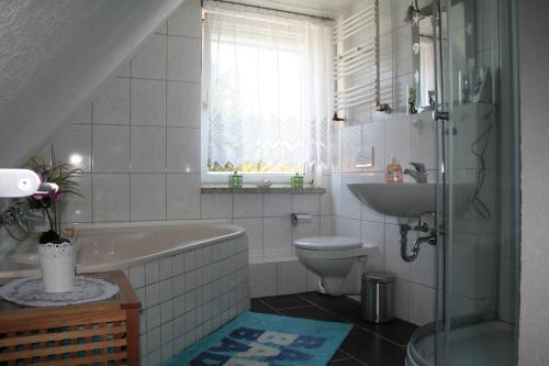 a bathroom with a tub and a toilet and a sink at Haus Stricker in Sagard