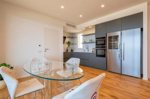 a kitchen and dining room with a glass table and white chairs at The Fetch - Residenze Esclusive sull'Acqua in Alghero