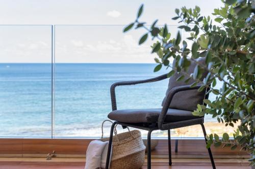 a black chair in front of a window with the ocean at The Fetch - Residenze Esclusive sull'Acqua in Alghero