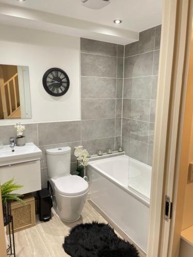 a bathroom with a toilet and a tub and a sink at Cosy Bedrooms in Manchester