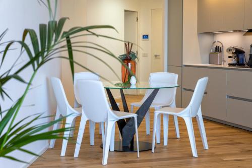 a dining room with a glass table and white chairs at The Fetch - Residenze Esclusive sull'Acqua in Alghero