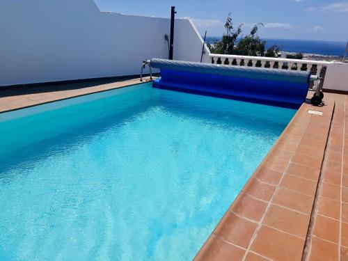 a swimming pool with blue water on the side of a house at Villa Feliza in Güime