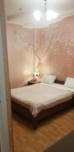 a bedroom with a bed with a tree on the wall at Elena in Kherson