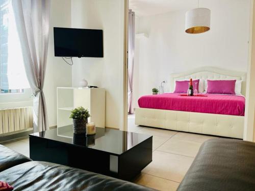 un soggiorno con letto con lenzuola rosa di Grazioso bilocale in centro storico a Verbania
