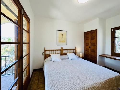 een slaapkamer met een bed met witte lakens en een raam bij La Paliane in Calonge
