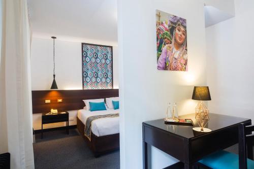 ein Hotelzimmer mit einem Bett und einem Schreibtisch mit einem Tisch sidx sidx in der Unterkunft SACHA Centric in Cusco