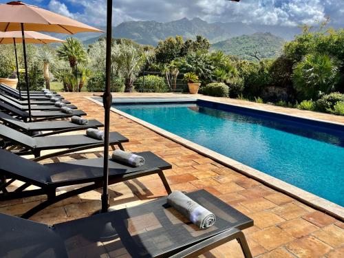 a swimming pool with lounge chairs and an umbrella at Domaine du Reginu in Santa-Reparata-di-Balagna