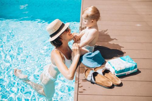 uma mulher e uma criança sentadas ao lado de uma piscina em SUNSEA - Enjoy Your Family em Capo Vaticano