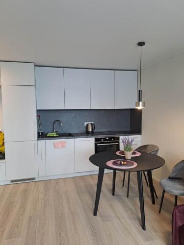a kitchen with a table and a kitchen with white cabinets at Naujai įrengtas jaukus dviejų kambarių butas in Šiauliai