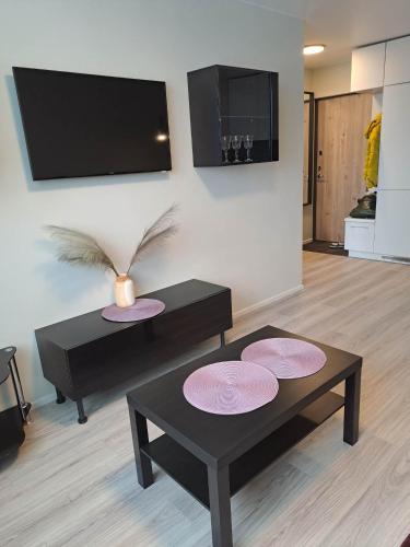 a living room with two tables and a tv at Naujai įrengtas jaukus dviejų kambarių butas in Šiauliai