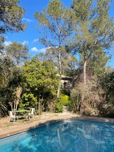 a swimming pool with a table and chairs and trees at Oustal du pic saint loup in Saint-Jean-de-Cuculles
