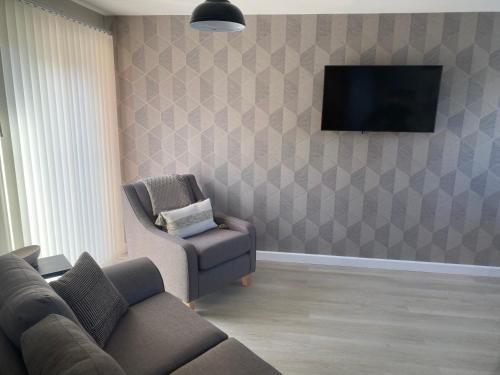 a living room with a couch and a chair and a television at Chapel Court Apartments in Cannock