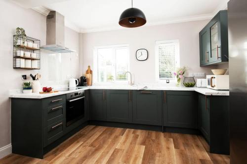a kitchen with green cabinets and a wooden floor at Large 5 Bedroom House - Alnwick in Alnwick