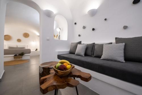 a living room with a couch and a bowl of fruit on a table at Virginia's Cave Villas in Oia